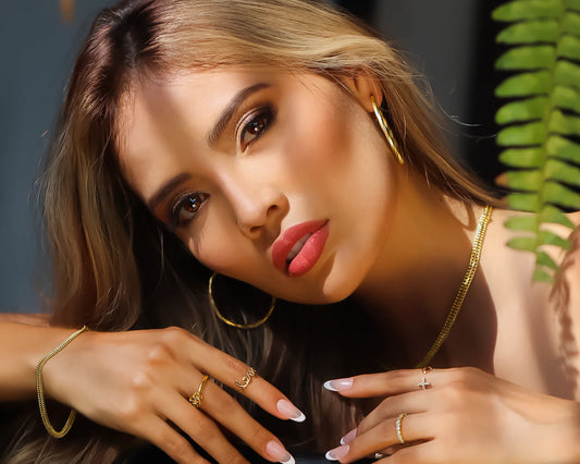 Imagen de una mujer modelo usando joyas en oro 18 quilates como, candongas, anillos, pulseras y cadenas de Joyería Caracas.