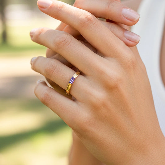 Mano de una modelo usando un anillo en oro amarillo con cristal purpura de Joyería Caracas.