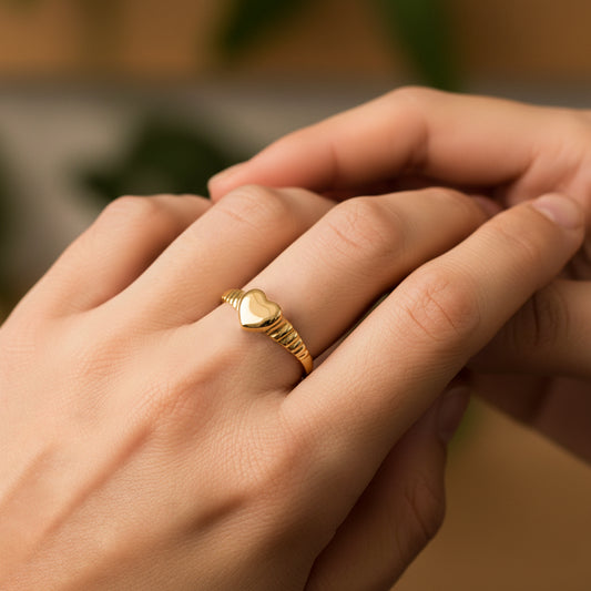 Mano de mujer usando un anillo con la forma de un corazón en el centro en oro amarillo de 18 quilates de Joyería Caracas.