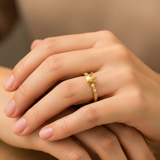 Mano de mujer usando un anillo con la forma de corona en el centro en oro amarillo de 18 quilates y cristales de color blanco de Joyería Caracas.