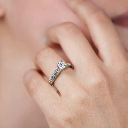Mano de mujer usando un anillo solitario en oro blanco de 18 quilates con Diamante en el centro de color blanco y Diamantes en los laterales de color blanco de Joyería Caracas.