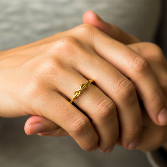 Mano de mujer usando un anillo con la forma de un infinito en oro amarillo de 18 quilates de Joyería Caracas.