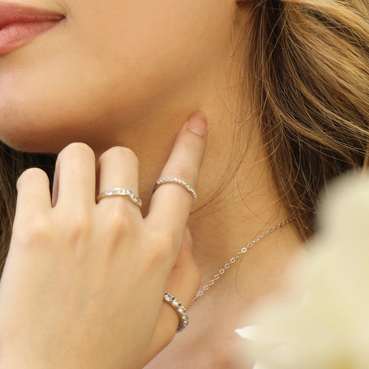 Mano de mujer usando un anillo en oro blanco de 18 quilates con cristales de color blanco de Joyería Caracas.