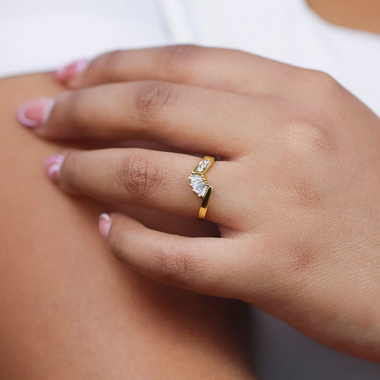 Mano de mujer con anillo pisargolla en oro amarillo de 18 quilates con cristal en un lateral de color blanco y cristales en forma de trapecios de color blanco de Joyería Caracas.