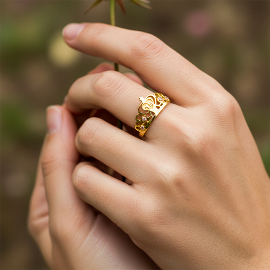 Mano de mujer usando un anillo con forma de corona en oro amarillo de 18 quilates con cristales rosados de Joyería Caracas.