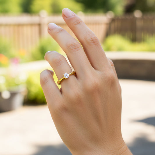 Mano de modelo usando un anillo solitario en oro amarillo de 18 quilates con cristal de Joyería Caracas.