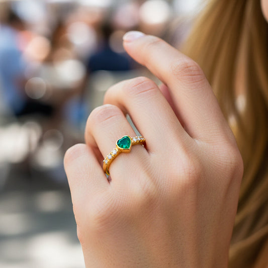 Mano de modelo usando un anillo en oro amarillo de 18 quilates con Esmeralda en forma de corazón con cristales de Joyería Caracas.