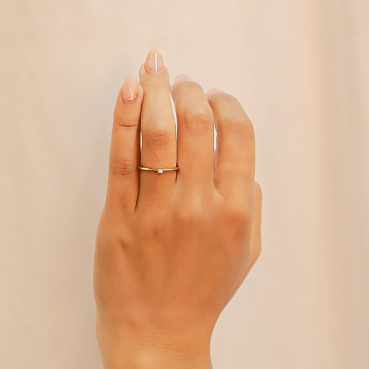 Mano de mujer usando un anillo de compromiso en oro amarillo de 18 quilates con Diamante en el centro de color blanco de Joyería Caracas.