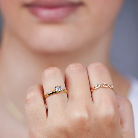 Mano de mujer usando un anillo solitario clásico en oro amarillo de 18 quilates con cristal en el centro de color blanco de Joyería Caracas.