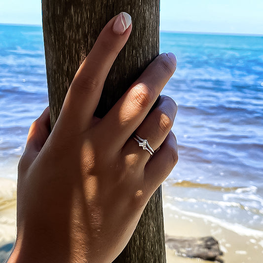 Mano de mujer con anillo con forma de corazón en el centro en oro blanco de 18 quilates y 3 Diamantes.