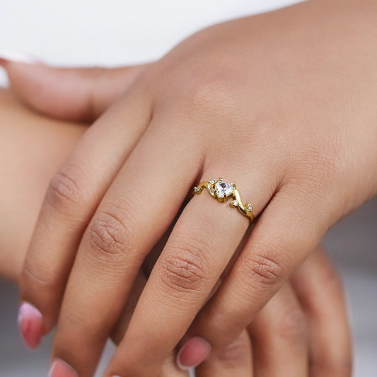 Mano de mujer usando un anillo en oro amarillo de 18 quilates con forma de ramas, Diamante en el centro en forma de corazón y Esmeraldas en las hojas de color verde de Joyería Caracas.