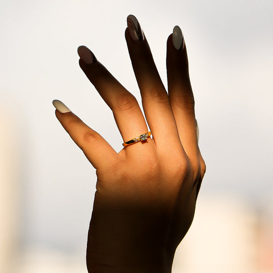 Mano de mujer con anillo en oro amarillo de 18 quilates con Diamantes de color blanco en el centro y laterales, fabricado en Joyería Caracas.