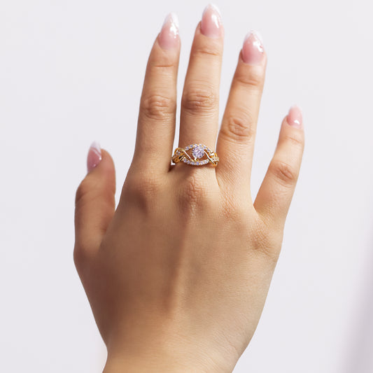 Mano de mujer con anillo en oro amarillo de 18 quilates con diseño de flechas entrelazadas, cristal de color blanco en el centro y alrededor de el.