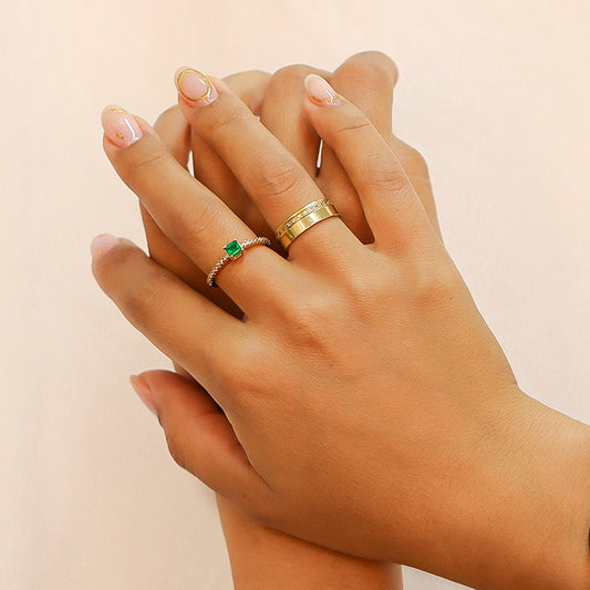 Mano de mujer con anillo en oro amarillo de 18 quilates con Esmeralda en el centro en forma cuadrada con cristales de color blanco alrededor.