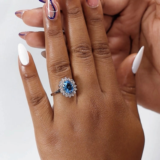 Mano de mujer usando un anillo de compromiso en oro blanco de 18 quilates con Topacio en el centro en forma de óvalo y Diamantes alrededor de color blanco de Joyería Caracas.