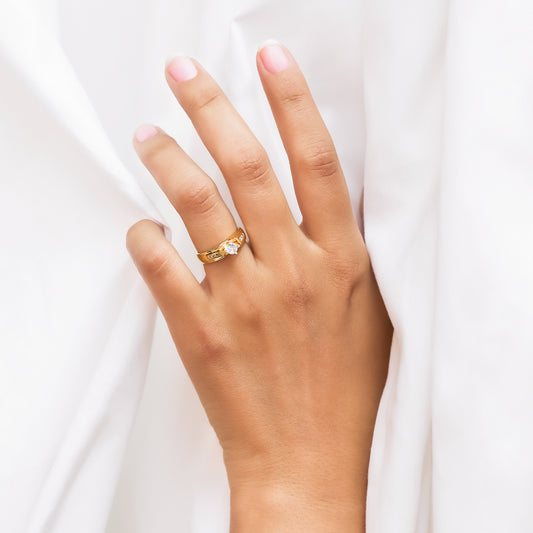 Mano de mujer con anillo en oro amarillo de 18 quilates con cristal de color blanco en el centro y cristales de color blanco a los laterales.