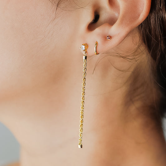 Oreja de mujer con topito en forma de corazón en oro amarillo de 18 quilates con 3 cristales de color rojo.