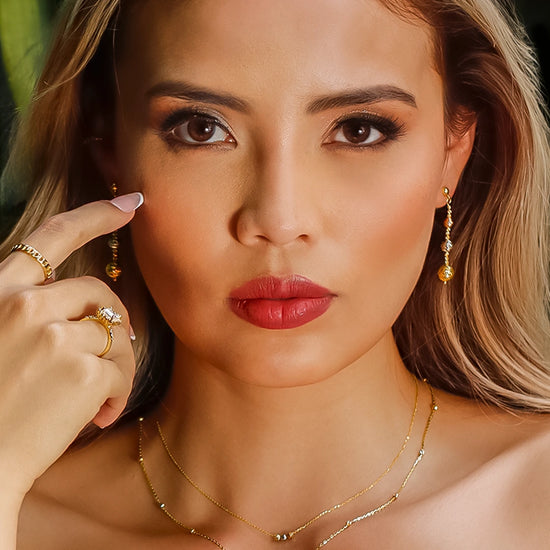 Oreja de mujer usando aretes de esferas diamantadas en degrade 3 oros en 18 quilates en Joyería Caracas.