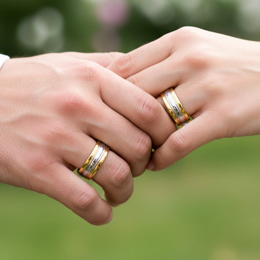 Manos de una pareja usando unas argollas de matrimonio en oro amarillo y blanco de 18 quilates de Joyería Caracas.