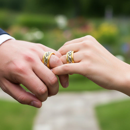 Manos de una pareja usando unas argollas de matrimonio en oro amarillo y con un trenzado en oro blanco de 18 quilates de Joyería Caracas.