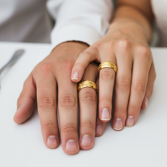 Manos de una pareja usando unas argollas en oro amarillo de 18 quilates de Joyería Caracas.