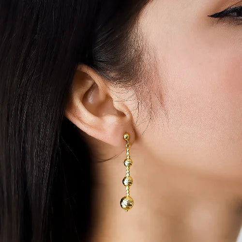 Un arete en oro con esferas de diferentes tamaños