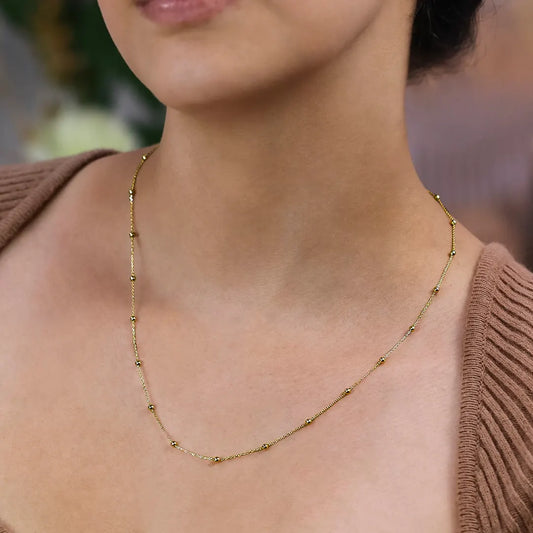 Cuello de mujer usando una cadena de esferas lisas de 50cm de largo en oro amarillo de 18 quilates de Joyería Caracas.
