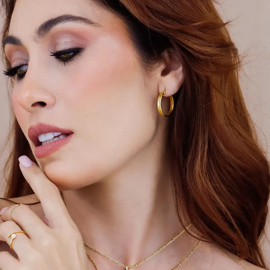 Oreja de mujer usando una candonga cuadrada de tubo plana en oro amarillo de 18 quilates de Joyería Caracas.