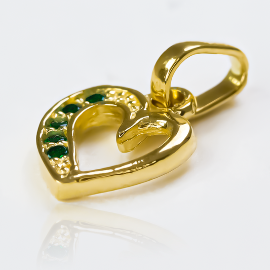 Dije Green heart cristal half JT de Joyería Caracas es el epitome de elegancia y lujo. Con su acabado en Oro 18K y cristal verde, cuenta con garantía de por vida.
