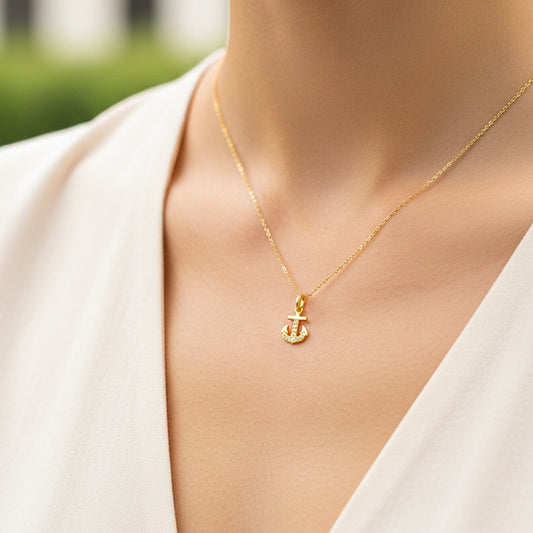 Cuello de modelo usando una cadena con un dije en forma de ancla en oro amarillo con cristales de 18 quilates de Joyería Caracas.