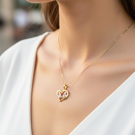Cuello de modelo usando una cadena con un dije en forma de corazón con angelitos en oro amarillo, blanco y rosa de 18 quilates de Joyería Caracas.