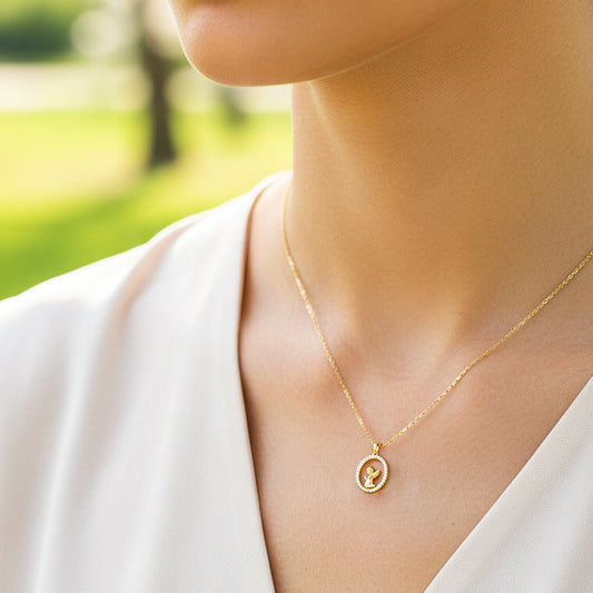 Cuello de modelo usando una cadena con un dije en forma de ángel rezando en oro amarillo de 18 quilates con cristales de Joyería Caracas.