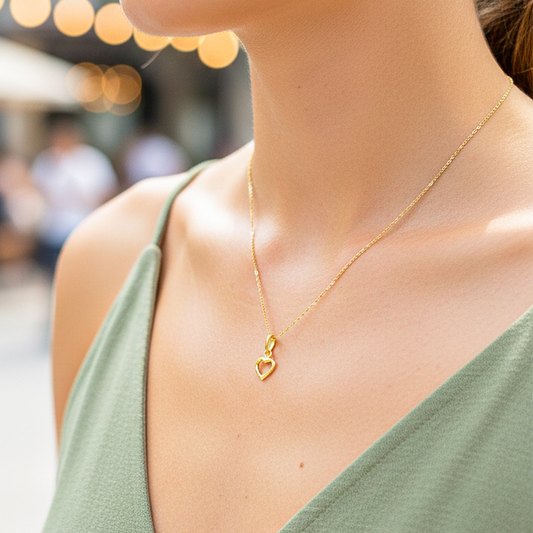Cuello de modelo usando una cadena con un dije en forma de corazón silueta liso en oro amarillo de 18 quilates de Joyería Caracas.