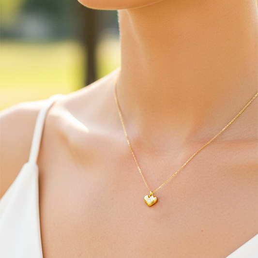 Cuello de modelo usando una cadena con un dije en forma de corazón soplado en oro amarillo de 18 quilates con cristal de Joyería Caracas.