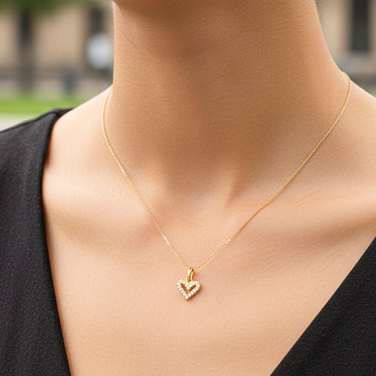 Cuello de modelo usando una cadena con un dije en forma de corazón en oro amarillo de 18 quilates con cristales de Joyería Caracas.