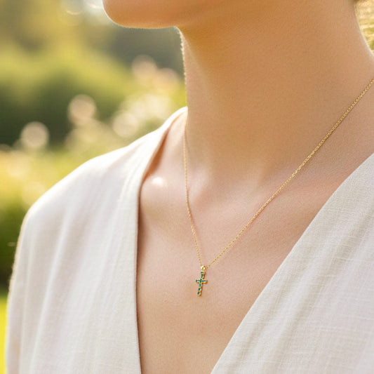 Cuello de modelo usando una cadena con un dije en forma de cruz oro amarillo de 18 quilates con Esmeraldas de Joyería Caracas.