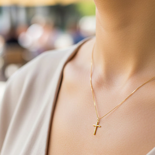 Cuello de modelo usando una cadena con dije en forma de cruz en oro amarillo de 18 quilates con crista blanco de Joyería Caracas.