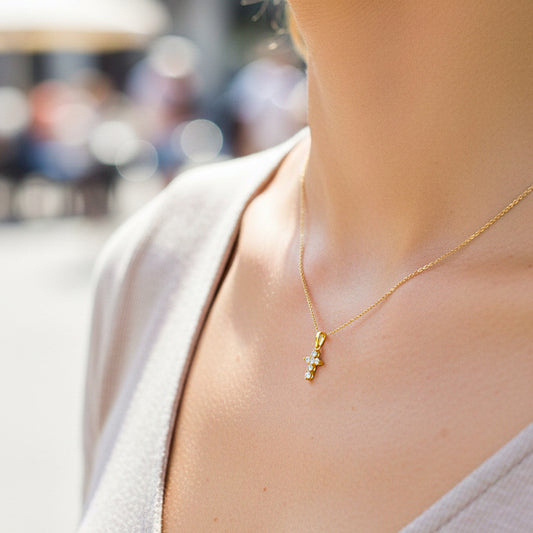 Cuello de modelo usando una cadena con un dije en forma de cruz en oro amarillo de 18 quilates con cristales de Joyería Caracas.