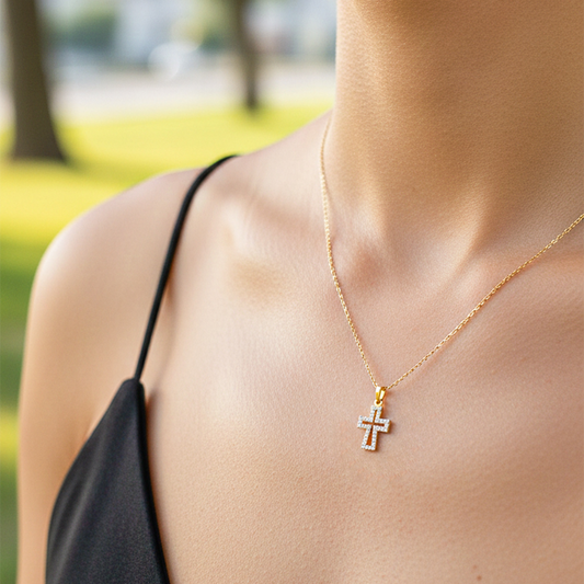 Cuello de modelo usando una cadena con un dije en forma de contorno de cruz en oro amarillo de 18 quilates con cristales de Joyería Caracas.