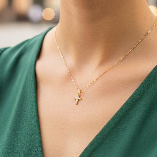 Cuello de modelo usando una cadena con un dije en forma de cruz en oro amarillo de 18 quilates con cristales de Joyería Caracas.