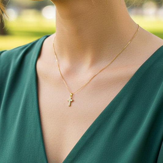 Cuello de modelo usando una cadena con un dije en forma de cruz en oro amarillo de 18 quilates con cristales de Joyería Caracas.