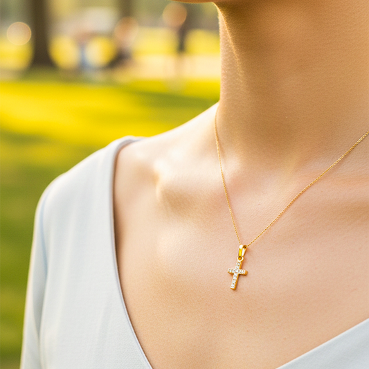 Cuello de modelo usando una cadena con un dije en forma de cruz en oro amarillo de 18 quilates con cristales de Joyería Caracas.
