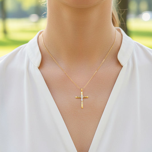 Cuello de modelo usando una cadena con un dije en forma de Cruz con Cristo en oro amarillo y blanco de 18 quilates de Joyería Caracas.