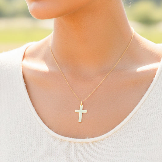Cuello de modelo usando una cadena con un dije en forma de cruz lisa en oro amarillo de 18 quilates de Joyería Caracas.