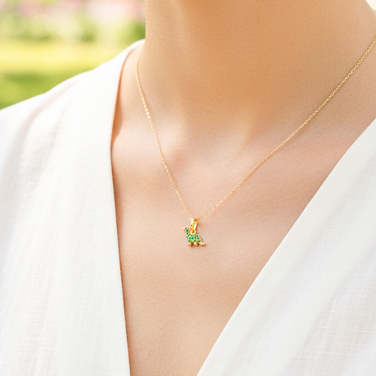 Cuello de modelo usando una cadena con un dije en forma de Dinosaurio en oro amarillo de 18 quilates con cristales de color verde de Joyería Caracas.
