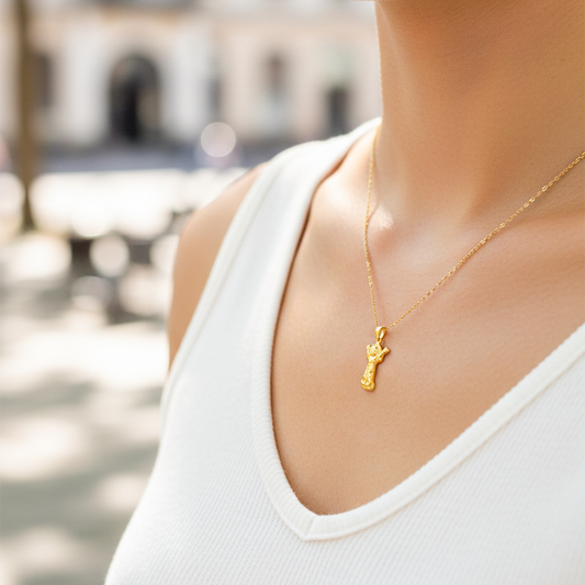 Cuello de modelo usando una cadena con un dije en forma del Divino Niño en oro amarillo de 18 quilates de Joyería Caracas.