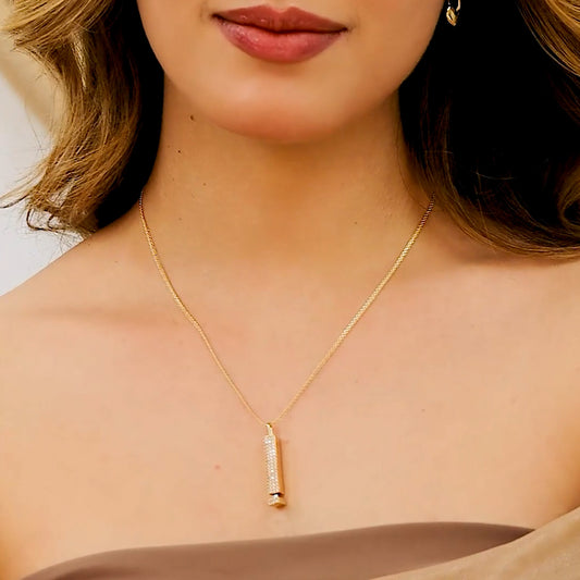 Cuello de mujer con cadena y dije en oro amarillo de 18 quilates en forma de epígrafe rectangular y vertical con cristales de color blanco, elaborado en Joyería Caracas.