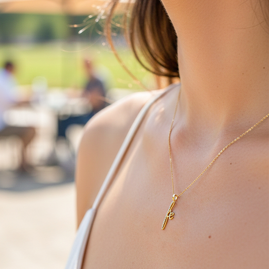 Cuello de modelo usando una cadena con un dije en forma de palabra fe en oro amarillo de 18 quilates con cristales de Joyería Caracas.