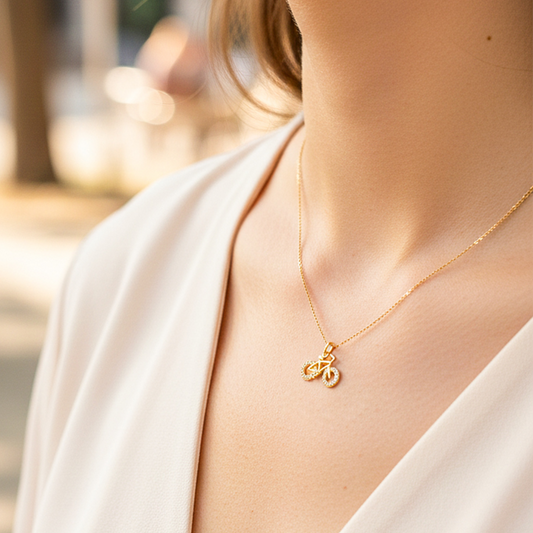 Cuello de modelo usando una cadena con un dije en forma de bicicleta en oro amarillo de 18 quilates con cristales de Joyería Caracas.
