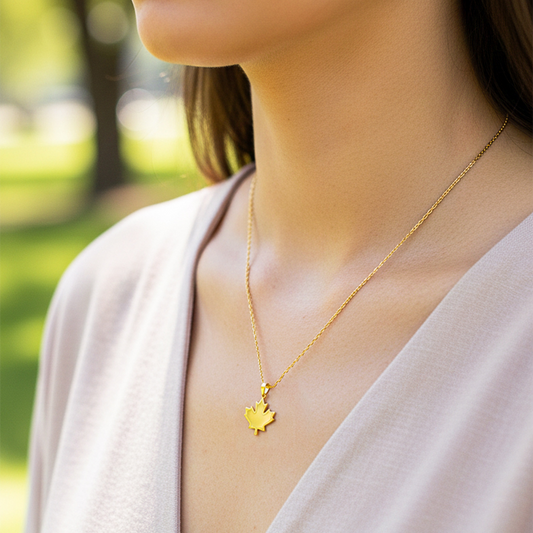 Cuello de modelo usando una cadena con un dije en forma de hoja de arce en oro amarillo de 18 quilates de Joyería Caracas.